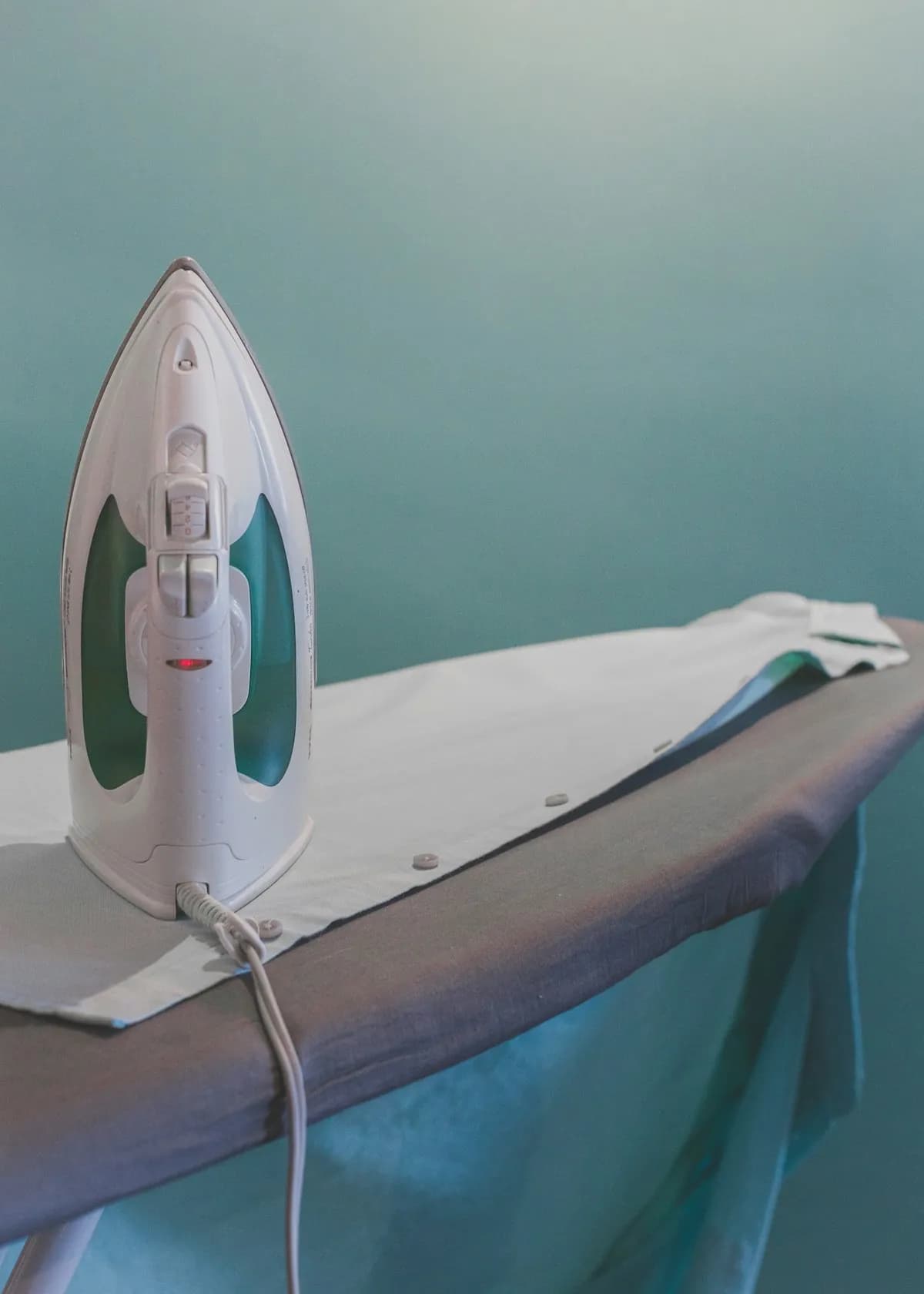 A steam iron resting on an ironing board