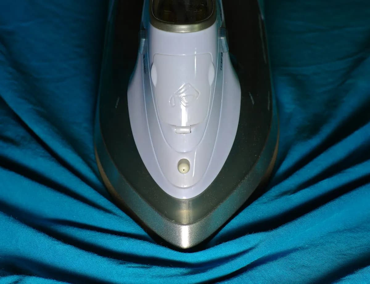 A steam iron pressing blue fabric